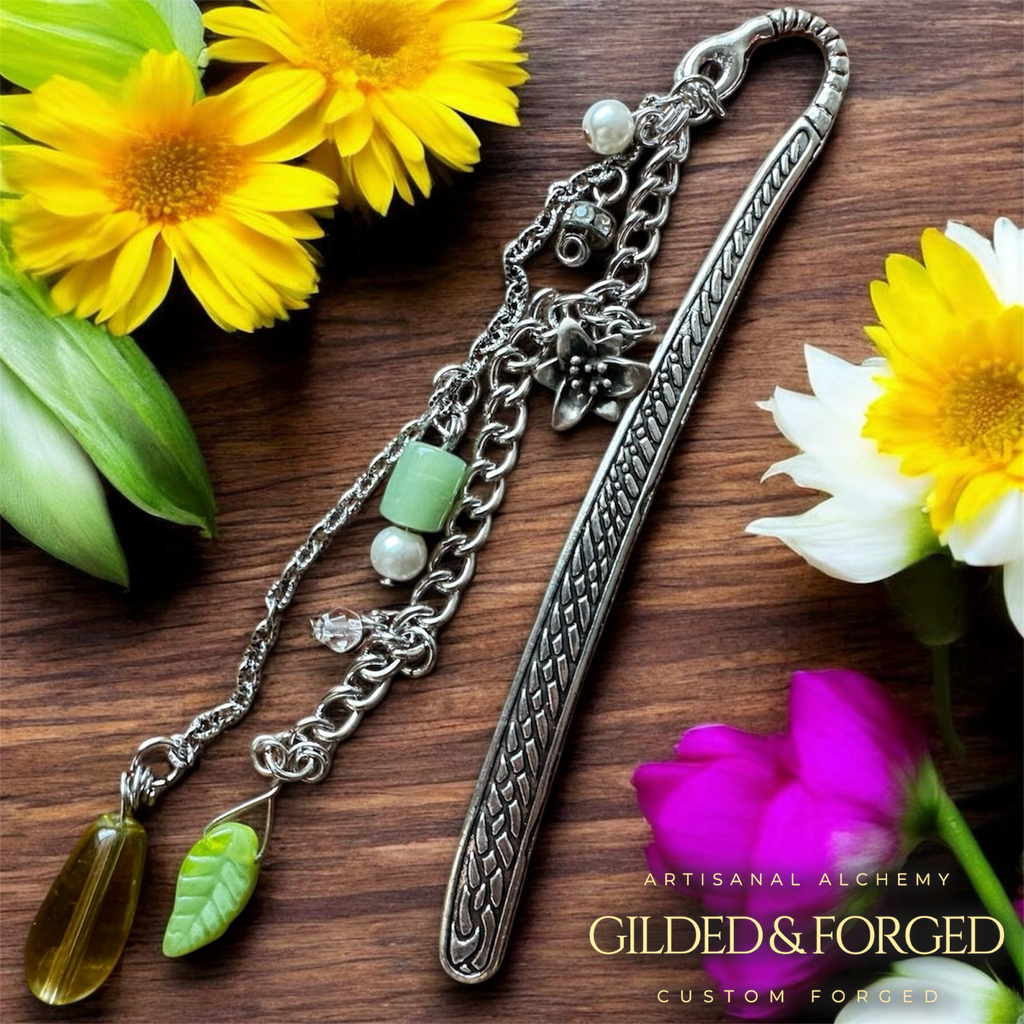 Silver heirloom bookmark with vintage glass leaf charm, green beads, and floral accents on wooden surface with flowers