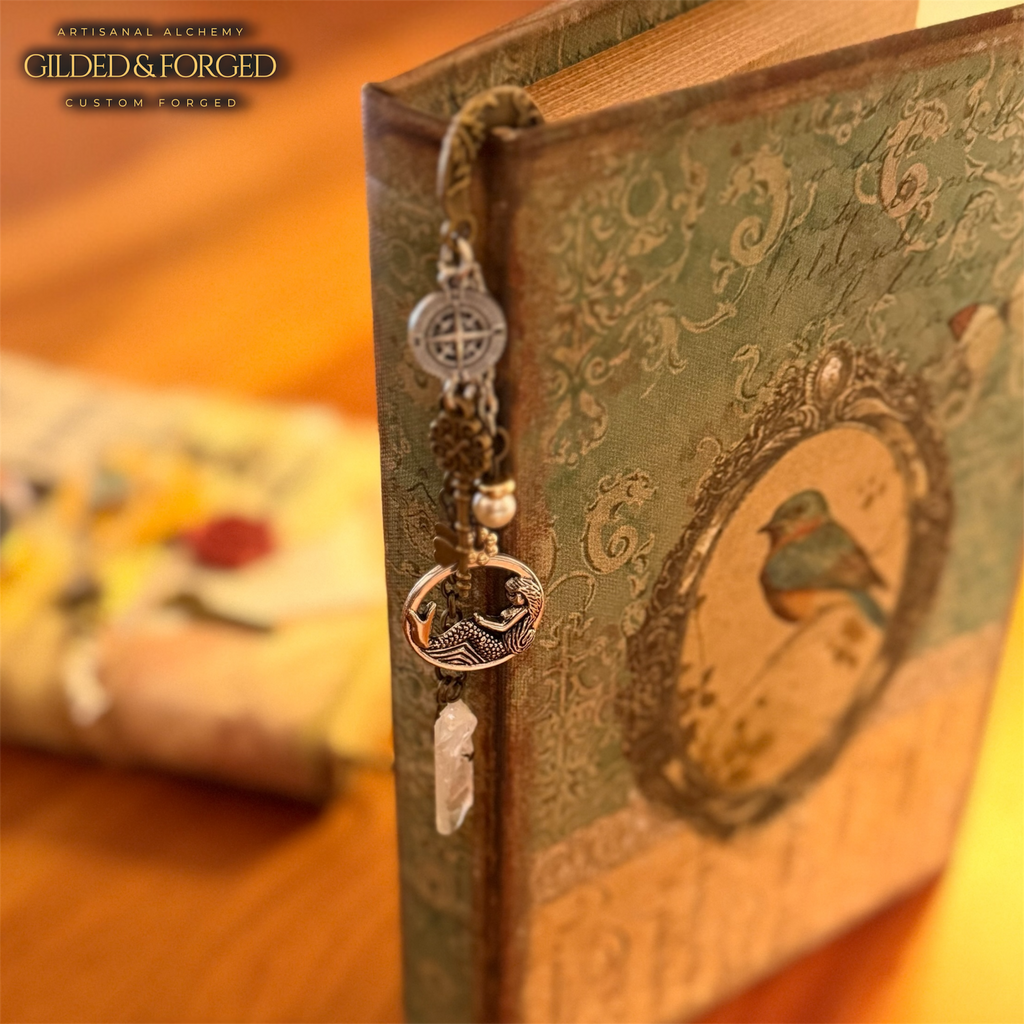 Handmade nautical metal bookmark with charms and quartz crystal resting on a vintage book